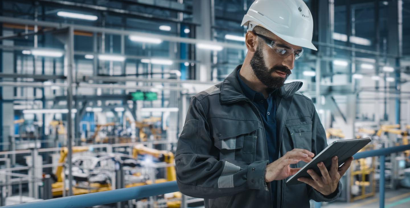 Défis ERP industriel : opérateur industriel consultant une tablette tactile dans une usine, face aux défis liés à l’intégration et à l’utilisation d’un ERP.