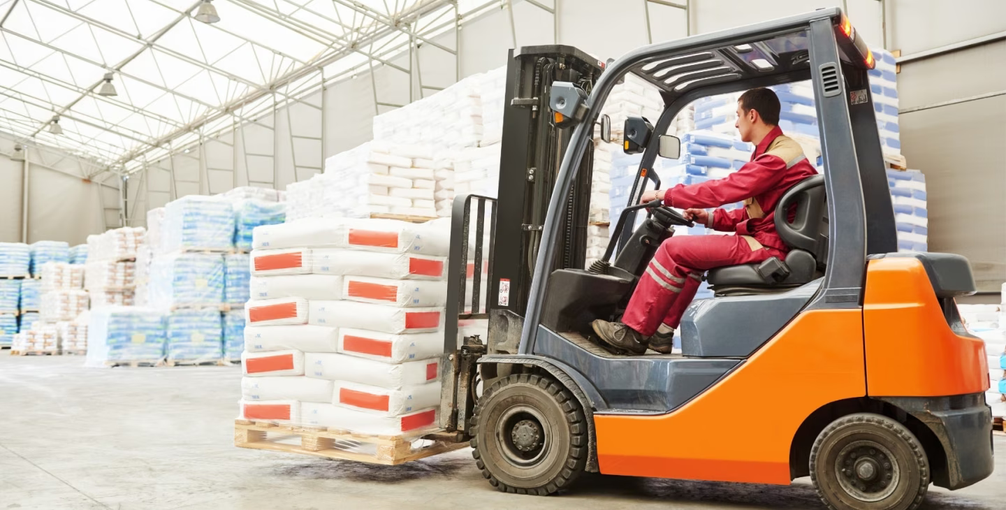 Opérateur utilisant un chariot élévateur pour déplacer des palettes dans un entrepôt avec le Logiciel ERP IFS Cloud.