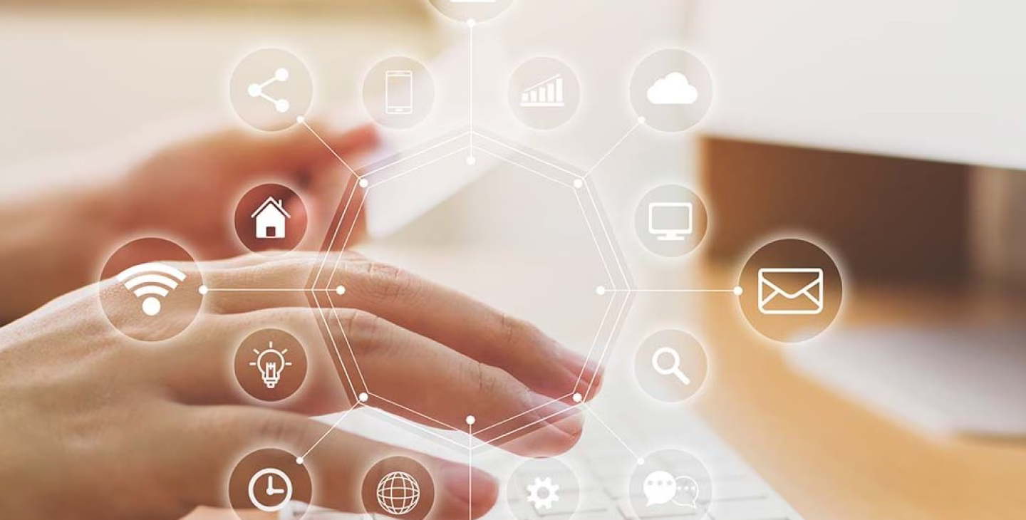 Mains tapant sur un clavier d’ordinateur avec des icônes digitales en surimpression représentant la connectivité, la messagerie, l’analyse, le cloud, la maison intelligente, et d’autres services numériques.