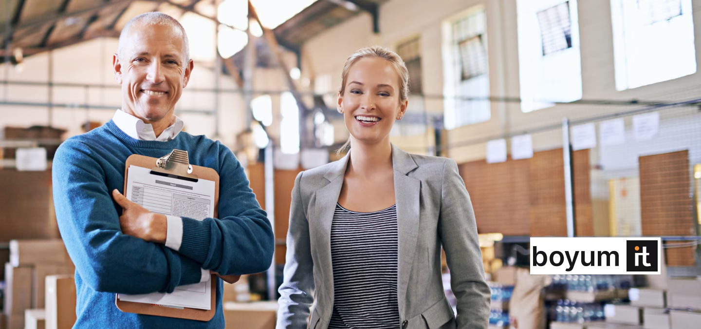 Deux responsables souriants dans un entrepôt utilisant les solutions Boyum IT intégrées à SAP Business One pour optimiser la gestion.