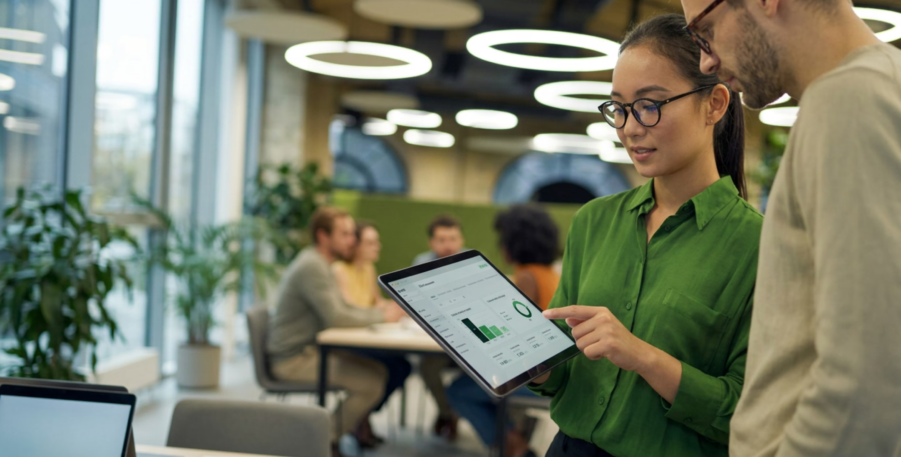 Deux collaborateurs consultent sur une tablette un tableau de bord pour piloter leur performance environnementale.