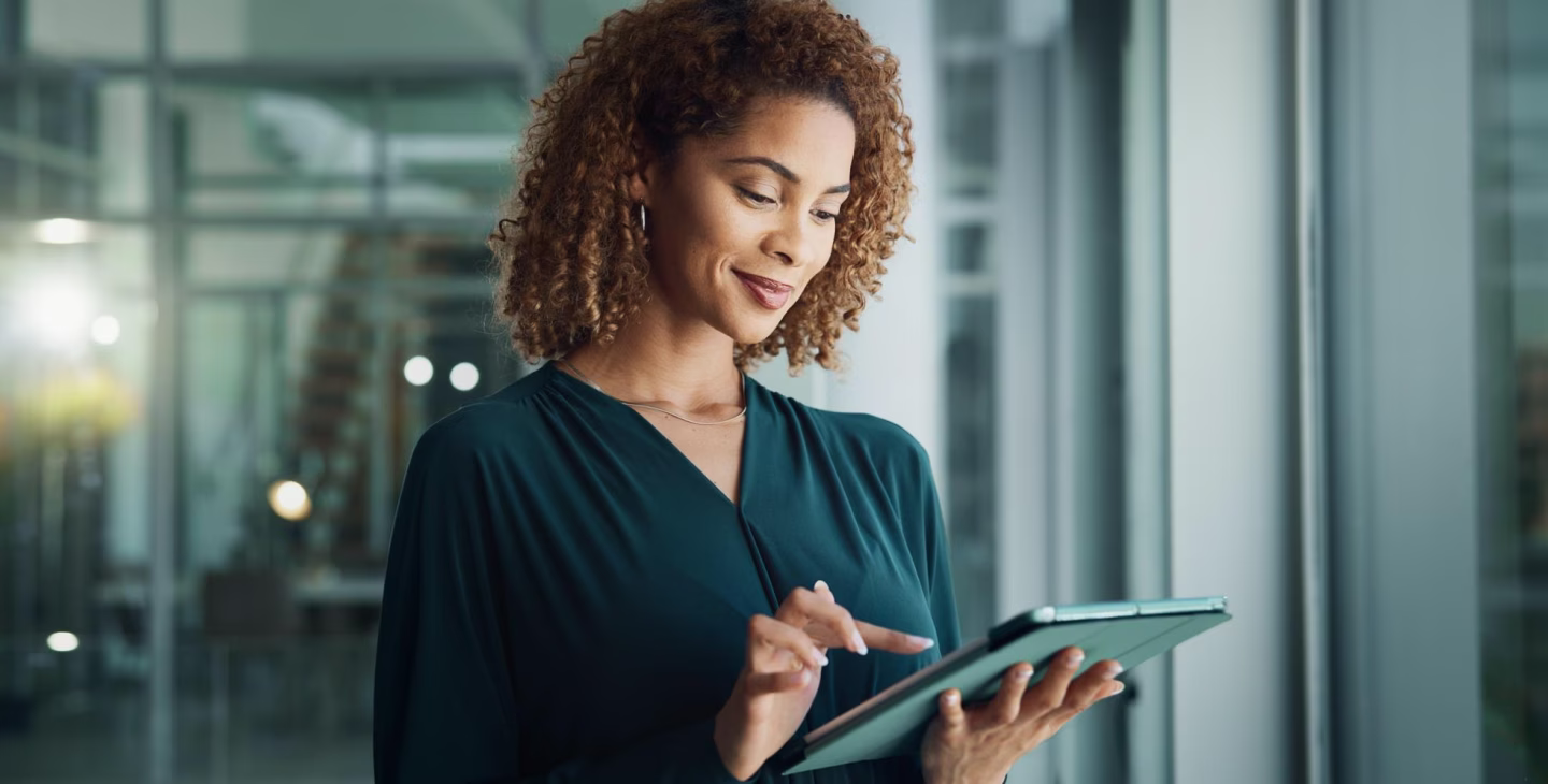 Utilisatrice consultant l’ERP Sage X3 2025 R2 sur tablette dans un environnement professionnel moderne.