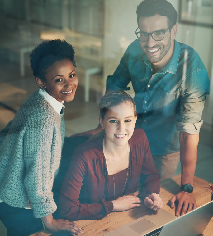 Une équipe de collaborateurs souriants travaillant ensemble devant un ordinateur portable avec SAP Business One Cloud.