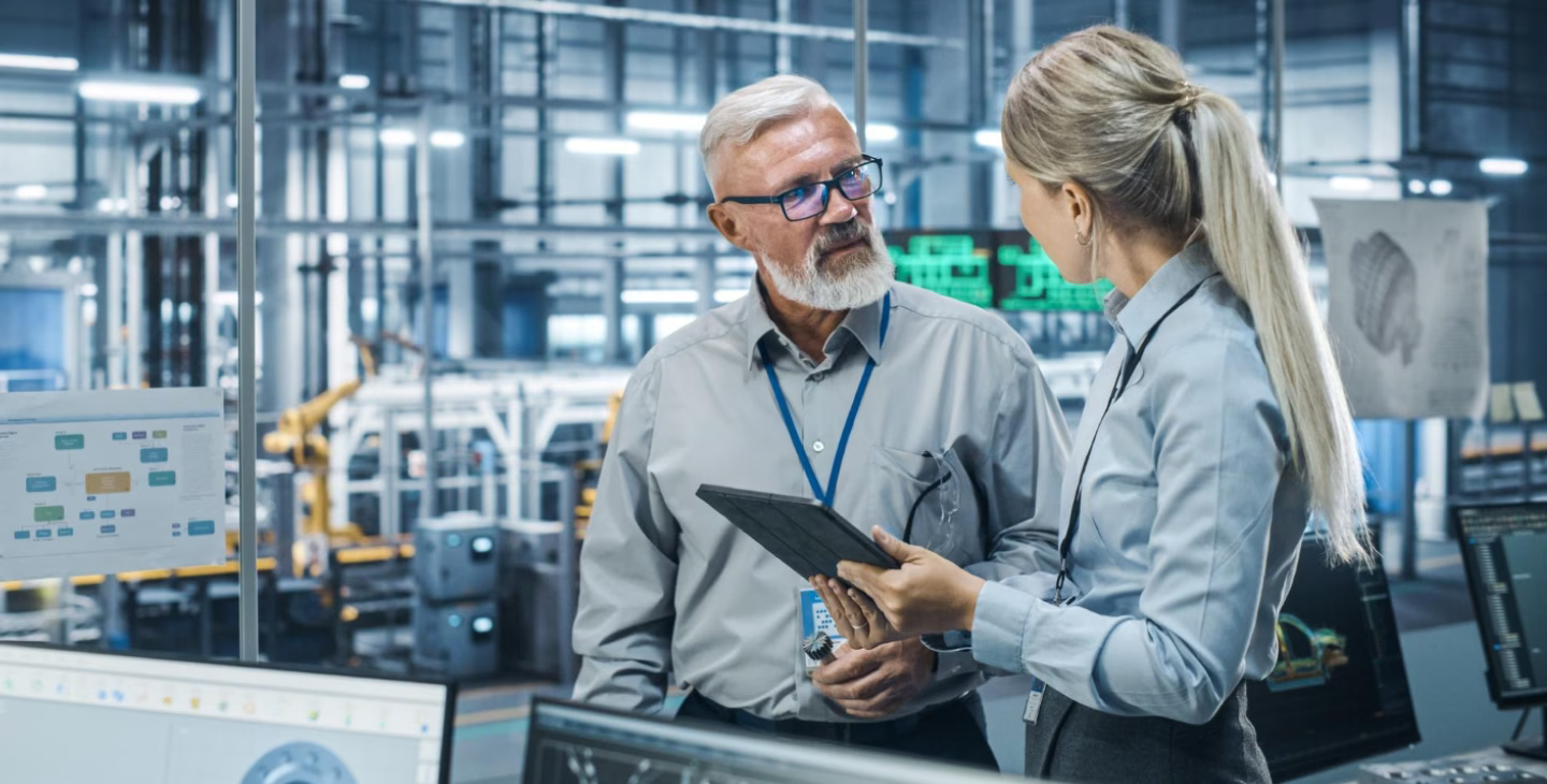 Collaborateurs échangeant autour d’une tablette dans un environnement industriel connecté à un ERP.